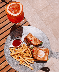 Sándwich Club con patatas y cóctel en Attitude Banús